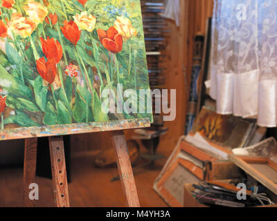 Unordentliche Artist Studio mit einem Stapel der Kunst arbeitet im Hintergrund und rote Blumen Malerei im Vordergrund. Stockfoto