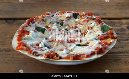 Ein rustikales vegetarische Pizza auf einen hölzernen Tisch. Stockfoto