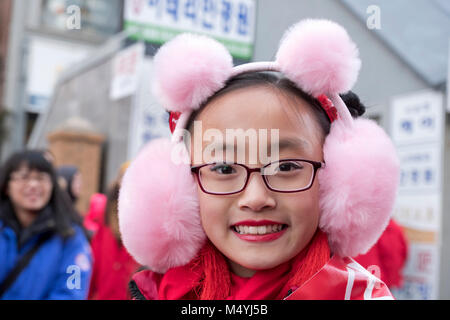 Ein niedliches die chinesisch-amerikanische Teenager mit Bunny eared Ohrenschützer auf der Chinese New Year Parade in Flushing, Queens, New York City