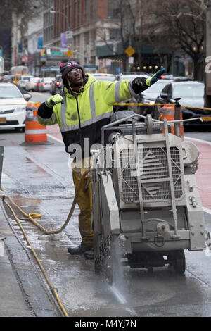 Ein Bauarbeiter an der West 23. Straße in Manhattan schneiden durch den Bürgersteig, um die elektrischen Leitungen, welche aktualisiert werden. Stockfoto