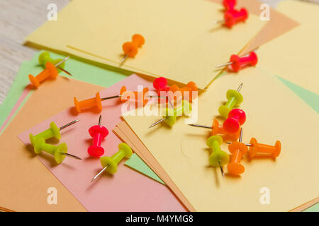 Stationäre, farbigen Reißzwecken liegen auf leere Aufkleber beachten Sie Papier. Strategie Planung Konzept. Stockfoto