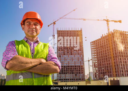 Die Builder in einem Schutzhelm, vor dem Hintergrund von Kränen und ein Gebäude Objekt Stockfoto