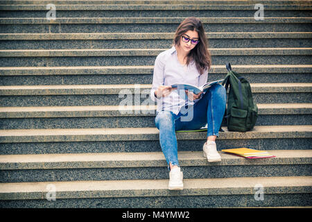 Schöne Mädchen, ein Student in der Brille liest ein Buch auf der Treppe. Allgemeine und berufliche Bildung. Indische College Stockfoto