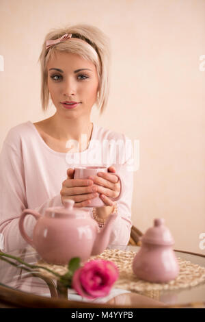 Junge schöne Frau mit Tee - Party in Rosa femininen Stil. Sie ist sehr satisfacted. Valentinstag oder dem Internationalen Frauentag feiern. Stockfoto