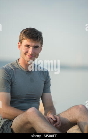 Müde junge Mann nach dem Joggen auf Sand am Strand Stockfoto