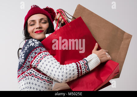 Shopping Winter Frau umarmt Einkaufstaschen mit Augen auf weißem Hintergrund geschlossen. Stockfoto