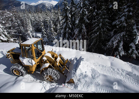 Noxon, Montana, USA. 19. Februar, 2018. Snow event. Ein Caterpillar 950 mit Gummibereifung artikuliert Lader Schneeräumen auf einem Berg Straße nördlich des Noxon, in Sanders County Montana. Der Lader wird von delbert Bowe von Libby, Montana betrieben. Die Straße ist in einem abgelegenen Teil des Schrankes Bergen, etwa 20 km nördlich von Noxon, Montana. Die Gegend war mit schweren Schnee, die aus dem Westen über das Wochenende kam, das mehrere Tage dauerte und Gedumpten über 20 Zentimeter Schnee in den Höhenlagen. Stockfoto