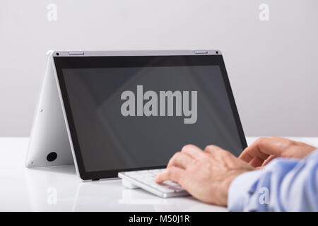 Hand Tippen auf der Tastatur Vor dem Hybrid Laptop über den Schreibtisch Stockfoto