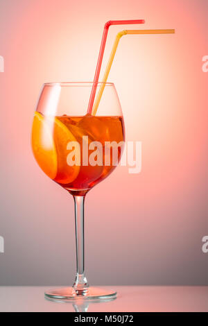 Trendy beliebte italienische trinken Sommer erfrischende schwach Alkoholischen Cocktail Aperol Spritz in ein Glas mit Eis dekoriert mit Orangenscheiben auf eine Farbe re Stockfoto