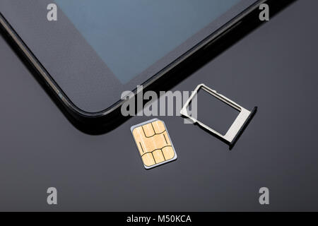 In der Nähe von Nano-SIM-Karte bereit zum Einfügen in Smart Phone über den Schreibtisch Stockfoto
