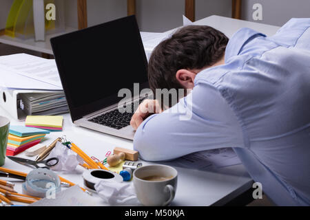 Close-up Erschöpft Geschäftsmann lehnte seinen Kopf auf Laptop über die unordentlichen Schreibtisch am Arbeitsplatz Stockfoto