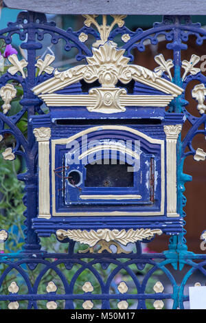 Eine alte, leere dekorative Postfach auf den Zaun. Blau- post-Box mit Verzierungen am Eisernen Tor. Stockfoto