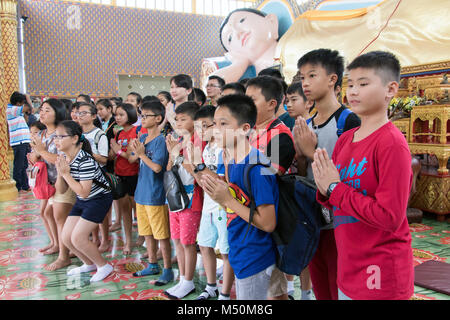 MALAYSIA, Penang, Nov 11 2017, liegenden Buddha Wat Chaiyamangalaram. Eine Klassenfahrt auf einem buddhistischen Kloster. Kinder beten, bevor der liegende Buddha. Stockfoto