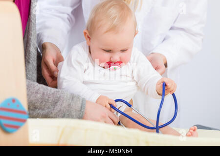 Süsse und gesunde Baby Mädchen spielen mit dem Stethoskop während r Stockfoto