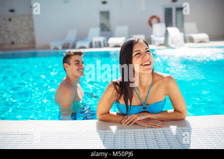 Lächelnd fröhliche Frau schwimmen in einem klaren Pool an einem sonnigen Tag. viel Spaß im Urlaub Pool Party. Freundliche Hündin genießen Sie erholsamen Urlaub. Summe Stockfoto