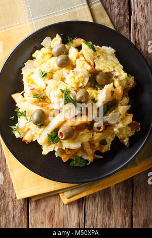 Portugiesische Essen: Gebratene geschreddert Kabeljau mit Pommes frites, Zwiebeln und Eier auf einer Platte close-up. Senkrechte Draufsicht von oben Stockfoto