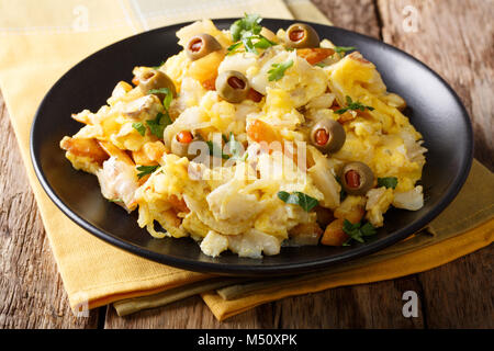 Gebratene geschreddert Kabeljau mit Kartoffeln, Zwiebeln, Ei und Oliven auf einen Teller auf den Tisch closeup. Horizontale Stockfoto