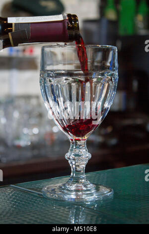 Rotwein ist in ein Glas an der Bar gegossen Stockfoto