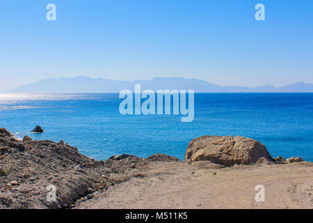 Schöne Küste mit blauem Wasser, blauer Himmel und die Silhouette der Insel am Horizont Stockfoto