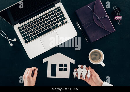 7/8 Schuß von geschäftsfrau am Arbeitsplatz mit Haus und Familie Versicherung Konzept isoliert auf Schwarz Stockfoto