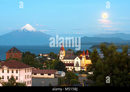 Mond steigt auf Puerto Varas am Ufer des See Llanquihue mit Vulkan Osorno im Rücken, X Region de Los Lagos, Chile Stockfoto