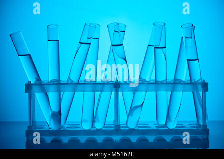 Glasröhrchen mit Flüssigkeit auf stehen für wissenschaftliche Analyse auf Blau Stockfoto