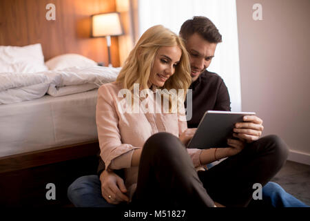 Glücklich liebend Paar auf dem Boden sitzend mit digitalen Tablet Stockfoto