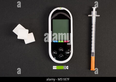 Insulin Spritze glucometer und weißen Würfel Zucker auf schwarzem Hintergrund als diabet und Hypoglykämie Konzept Stockfoto