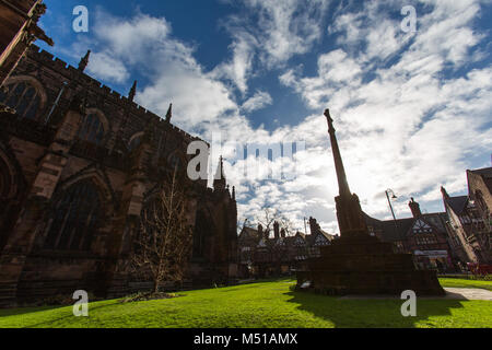 Stadt Chester, England. Silhouetted Ansicht des Memorial Cross im südlichen Garten Chester Cathedral, mit St. Werburgh Street im Hintergrund. Stockfoto