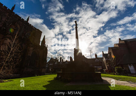 Stadt Chester, England. Silhouetted Ansicht des Memorial Cross im südlichen Garten Chester Cathedral, mit St. Werburgh Street im Hintergrund. Stockfoto