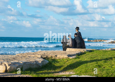 Religiöse Juden Familie an der Küste des Mittelmeers in Israel sitzen und beobachten die Wellen. Sunset Beach, Familie rest Tradition. Selektiver Fokus, Stockfoto