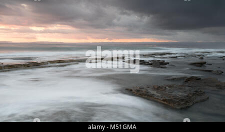 Felsigen Küste Meereslandschaft mit welligem Meer und Wellen auf die Felsen in einer dramatischen und schönen Sonnenuntergang an der Küste von Akrotiri in Limassol, Cyp Stockfoto