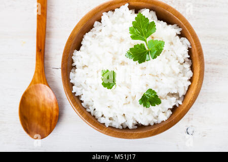 Gekochten Reis in eine hölzerne Schüssel und Löffel auf dem Tisch. Leckeres vegetarisches Abendessen. Stockfoto