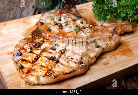 Schweinekoteletts Pfeffersteak Holzkohle Grill Feuer auf BBQ-Soße mit Außenbeleuchtung und Flash Beleuchtung hinzufügen. Stockfoto