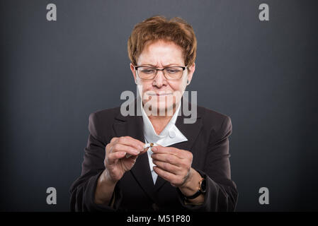 Business ältere Dame einen Cigarrete wie das Rauchen auf schwarzem Hintergrund Stockfoto