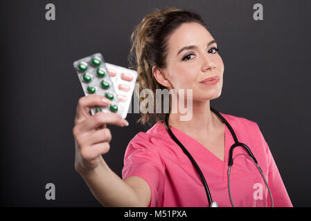 Portrait von schönen jungen Arzt holding Blister mit Pillen auf schwarzen Hintergrund mit copypsace Werbefläche Stockfoto