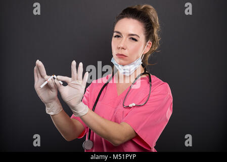 Portrait von attraktiven Dame Arzt brechen wie keine Zigarette rauchen Konzept auf schwarzem Hintergrund Stockfoto