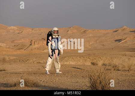 Ein analoger Astronaut, gekleidet in einen speziellen Raumanzügen, umrundet das Gelände der Mars-ähnlichen Forschungseinrichtung, die für den D-MARS (Desert Mars Analog Ramon Station) gebaut wurde, eine einzigartige Initiative für einen Lebensraum für Planetenforschung, der in einem isolierten Wüstengebiet im Ramon Crater in der Negev-Wüste gebaut wurde. Die Analogastronauten leben in der Forschungseinrichtung und können den Lebensraum nur in Raumanzügen verlassen. Während der Isolation führt das Team eine Reihe von wissenschaftlichen und technologischen Experimenten durch, in der Hoffnung, die Grundlagen für zukünftige bemannte Missionen zum Mars zu schaffen. Stockfoto