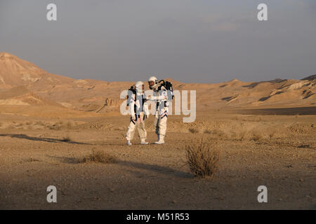 Analoge Astronauten, verkleidet in einem speziellen Raumanzügen, umherwandern das Gelände der Mars-ähnlichen Forschungseinrichtung für den D-MARS (Desert Mars Analog Ramon Station), eine einzigartige Initiative für einen Lebensraum für Planetenforschung, der in einem isolierten Wüstengebiet im Ramon Crater in der Negev-Wüste gebaut wurde. Die Analogastronauten leben in der Forschungseinrichtung und können den Lebensraum nur in Raumanzügen verlassen. Während der Isolation führt das Team eine Reihe von wissenschaftlichen und technologischen Experimenten durch, in der Hoffnung, die Grundlagen für zukünftige bemannte Missionen zum Mars zu schaffen. Stockfoto