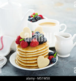 Stapel von Buttermilch Pfannkuchen mit herzförmige Plätzchen, frischen Beeren und Ahornsirup für Valentines Tag Frühstück Stockfoto