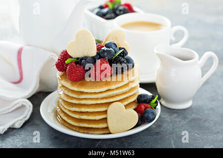 Stapel von Buttermilch Pfannkuchen mit herzförmige Plätzchen, frischen Beeren und Ahornsirup für Valentines Tag Frühstück Stockfoto