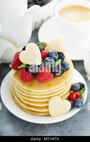 Stapel von Buttermilch Pfannkuchen mit herzförmige Plätzchen, frischen Beeren und Ahornsirup für Valentines Tag Frühstück Stockfoto