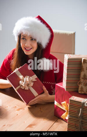 Junge hübsche Frau tragen Klausenmütze Verpacken Weihnachten Geschenk an ihrem Schreibtisch Stockfoto