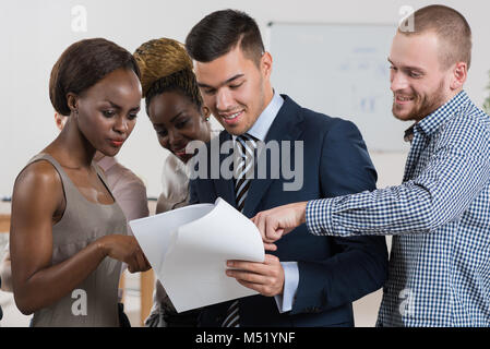Lächelnde Business-Team diskutieren, Dokumente und Berichte im Büro Stockfoto
