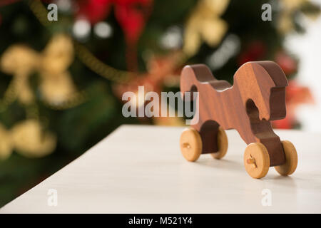 Vintage Wooden Horse auf Santa's Arbeitstisch, Weihnachtsbaum auf Hintergrund Stockfoto