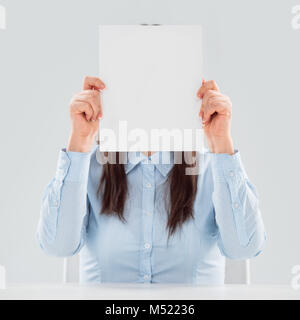 Portrait von Business woman holding leeres Blatt Papier vor ihrem Gesicht Stockfoto