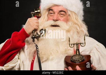 Portrait von Santa Claus die Telefonnummer gegen den dunklen Hintergrund Stockfoto