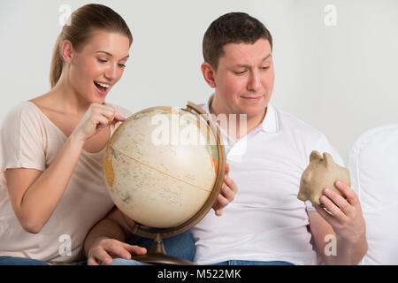 Portrait von Happy romantisches Paar zusammen zu Hause sitzen mit Globus Urlaub und Reise planen. Reisen Konzept Stockfoto