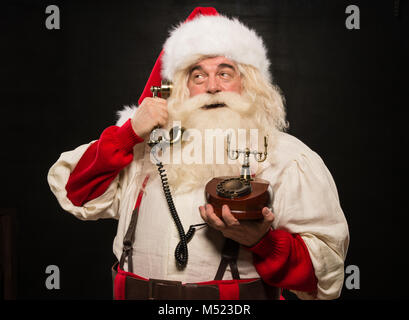 Portrait von Santa Claus die Telefonnummer gegen den dunklen Hintergrund Stockfoto
