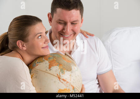 Portrait von Happy romantisches Paar zusammen zu Hause sitzen mit Globus Urlaub und Reise planen. Reisen Konzept Stockfoto